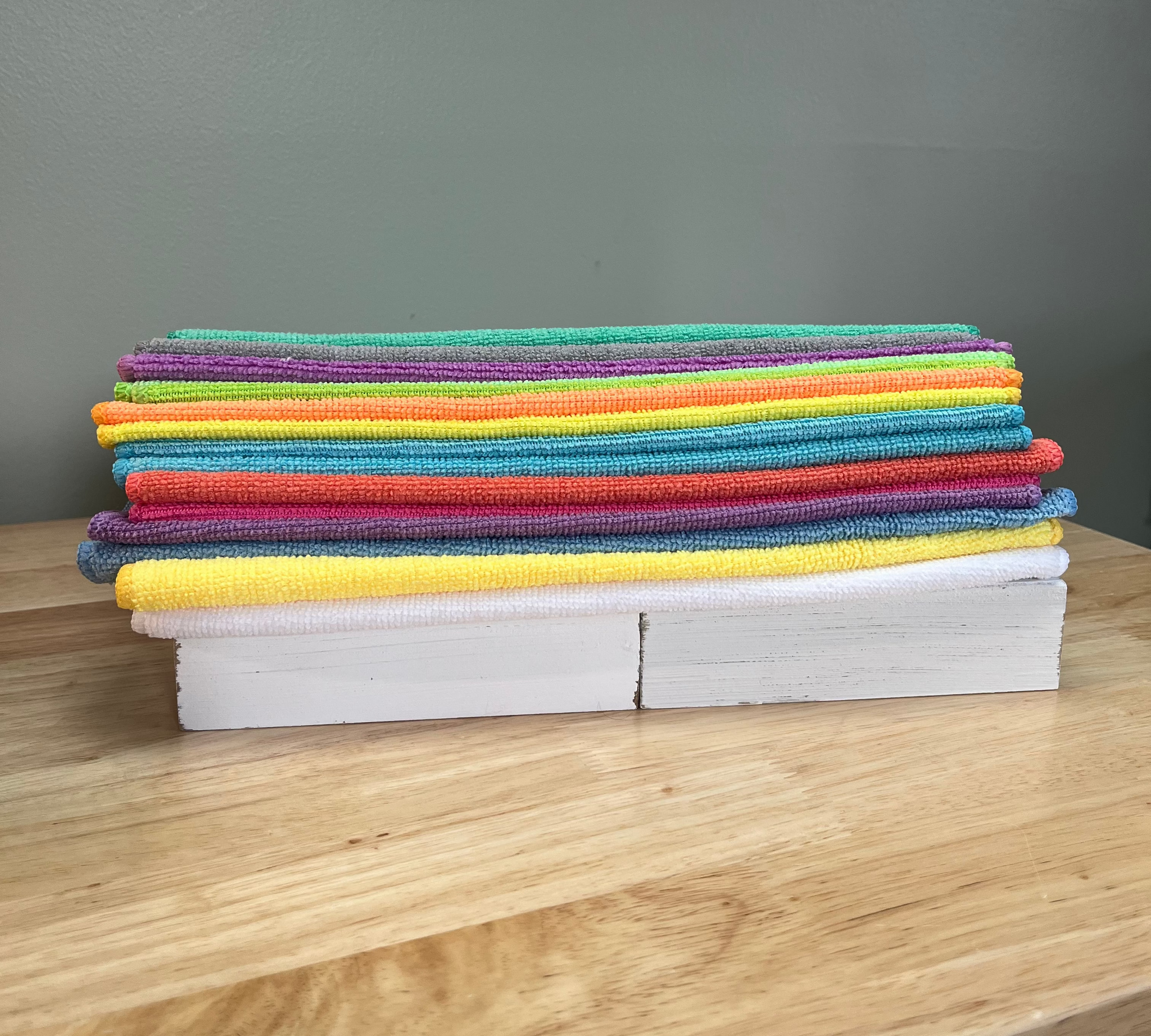 Stack of colorful cloths on a wooden surface with a gray wall background