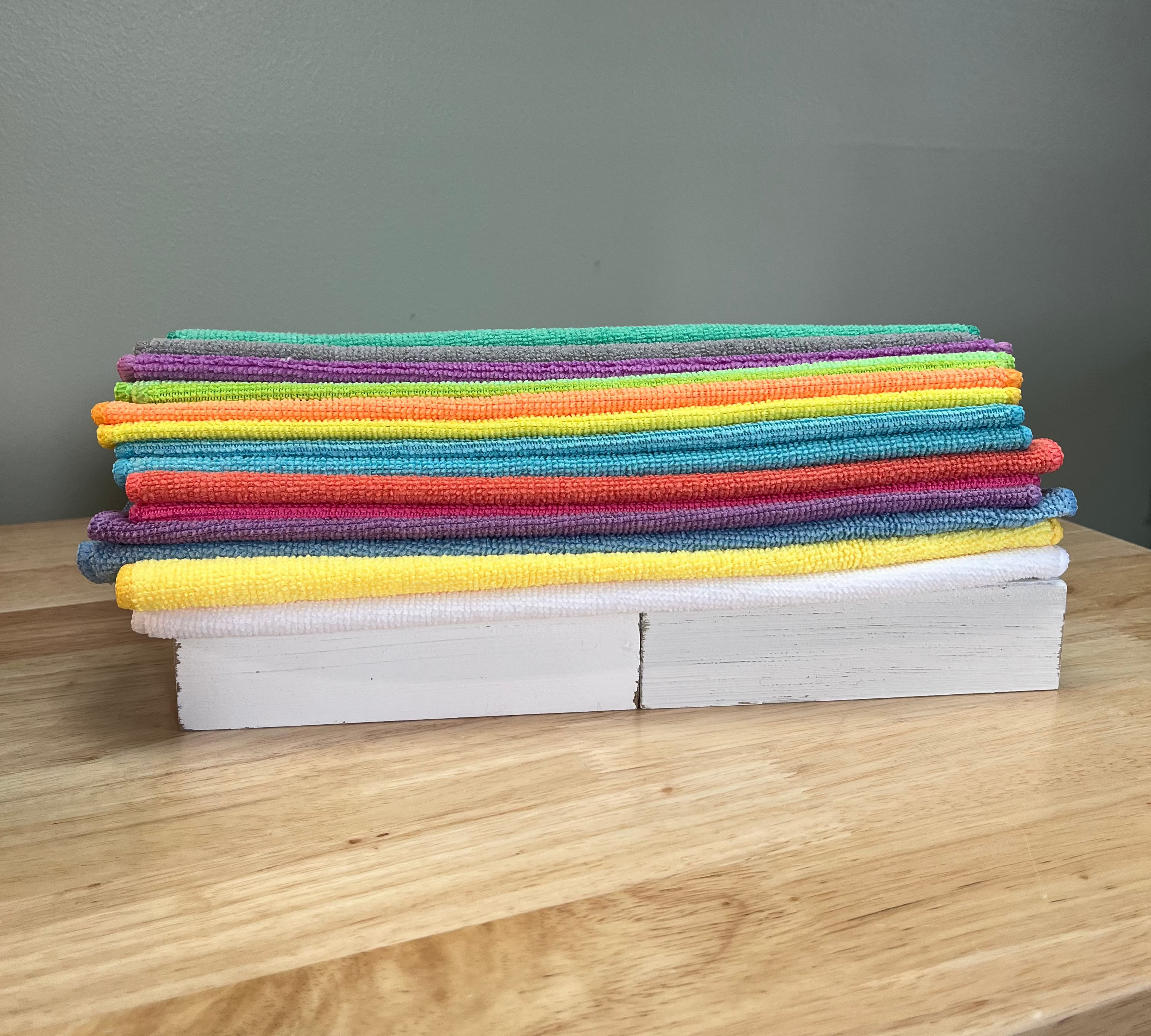Stack of colorful cloths on a wooden surface with a gray wall background